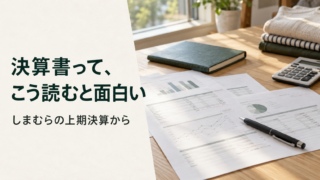 自然光の入る机で、決算資料と緑のノートを読む様子